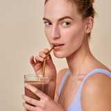 Vanessa Axente drinking the Essa World Vegan Protein Powder in Choco-spice flavour from a glass.