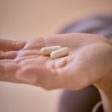 Two Essa World Inner Beauty Vitamin pills in a woman's palm.