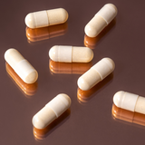 Essa World Inner Beauty Vitamin pills on a glass surface.