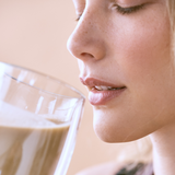 A woman drinking the Essa World vegan protein from a glass.